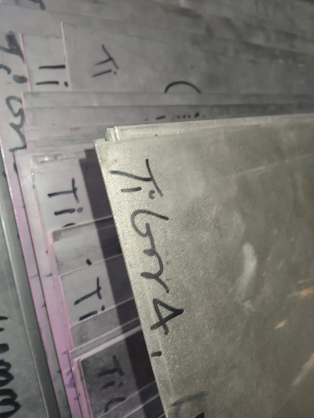 Titanium sheets in the warehouse, edge-marked Ti Gr 4 in marker pen